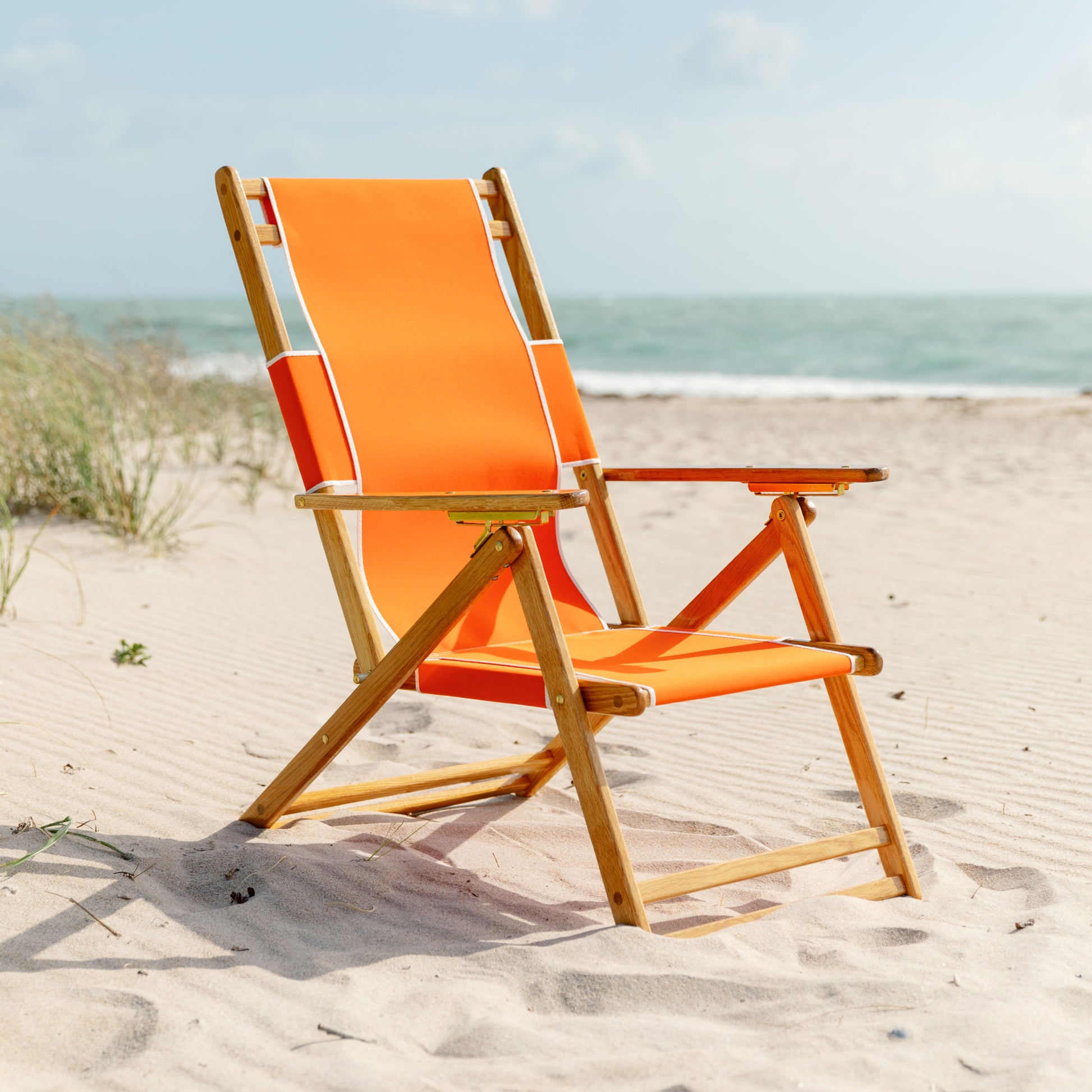 Coastsetter Beach Chair in Tangerine on the sand, upright without a leg rest